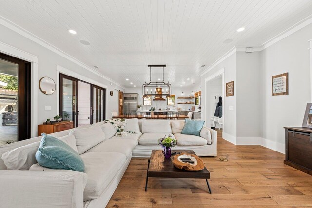 living room featuring light wood-type flooring, a chandelier, wooden ceiling, and crown molding