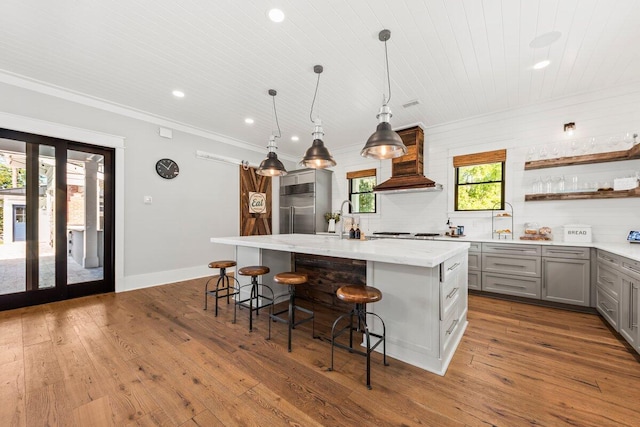 kitchen featuring an island with sink, a wealth of natural light, and premium range hood