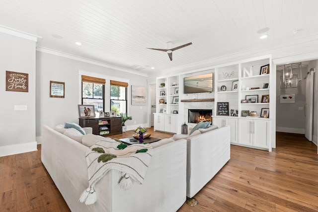 living room featuring light wood-type flooring, a fireplace, crown molding, and wooden ceiling