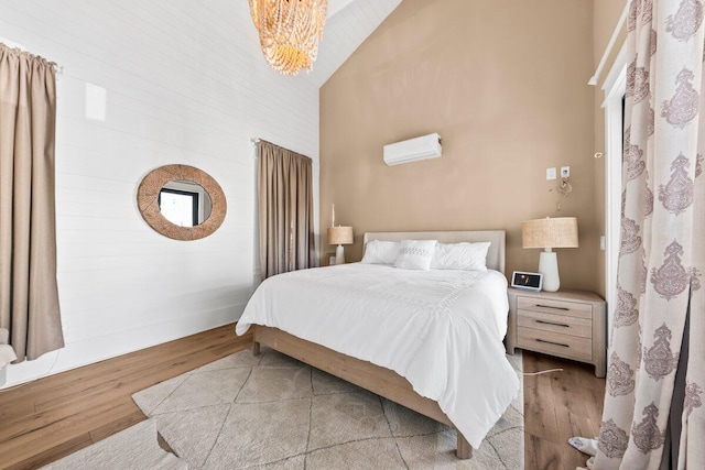 bedroom with high vaulted ceiling, light hardwood / wood-style floors, and an inviting chandelier