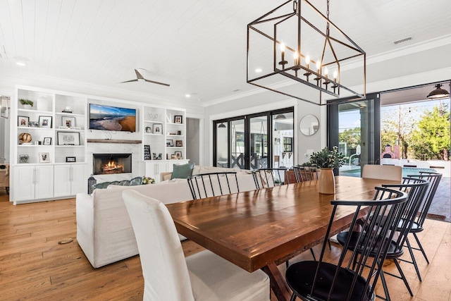 dining space featuring ornamental molding, a high end fireplace, wooden ceiling, and light hardwood / wood-style flooring