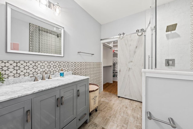 bathroom with wood-type flooring, vanity, tiled shower, and tile walls