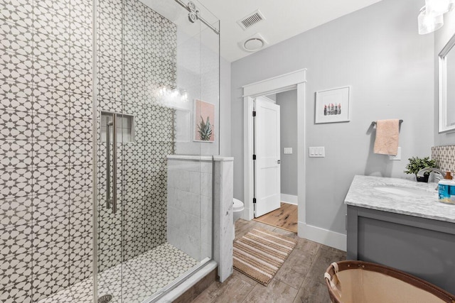 bathroom featuring toilet, an enclosed shower, vanity, and hardwood / wood-style flooring