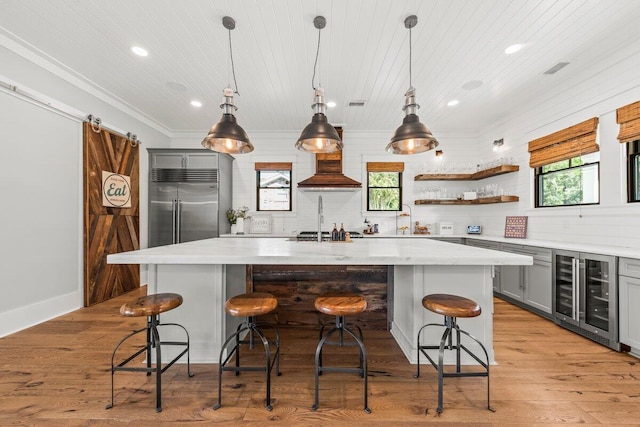 kitchen with gray cabinets, beverage cooler, a wealth of natural light, and a kitchen island with sink