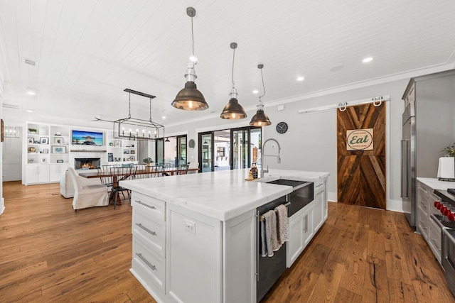 kitchen with dishwasher, decorative light fixtures, hardwood / wood-style flooring, and a kitchen island with sink