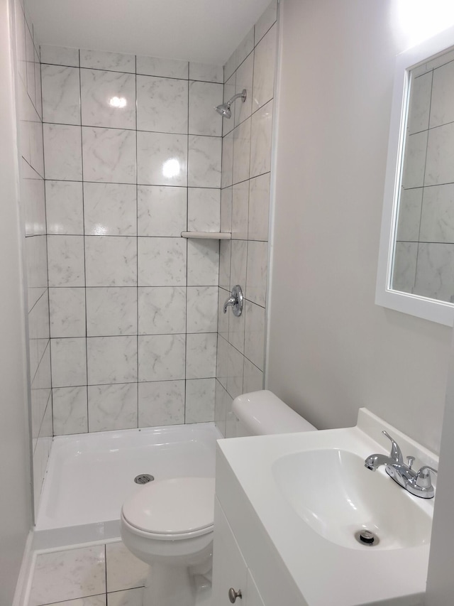 bathroom with vanity, tile patterned floors, toilet, and a tile shower