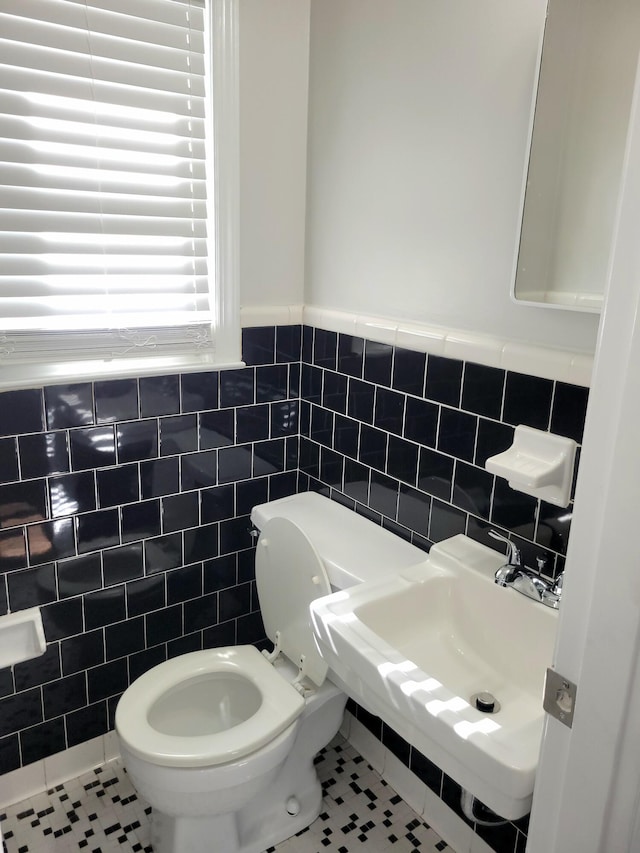 bathroom featuring toilet, tile walls, and tile patterned flooring