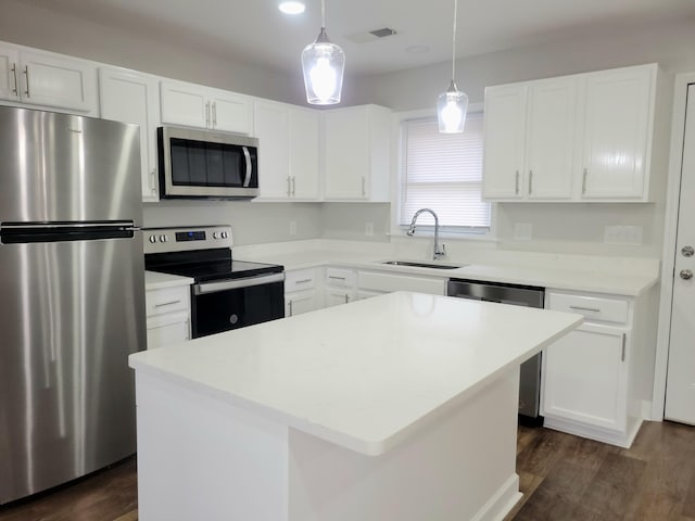 kitchen featuring a kitchen island, appliances with stainless steel finishes, dark hardwood / wood-style floors, pendant lighting, and sink