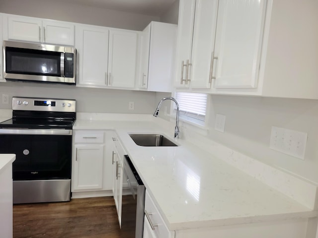 kitchen with appliances with stainless steel finishes, light stone countertops, sink, white cabinets, and dark wood-type flooring