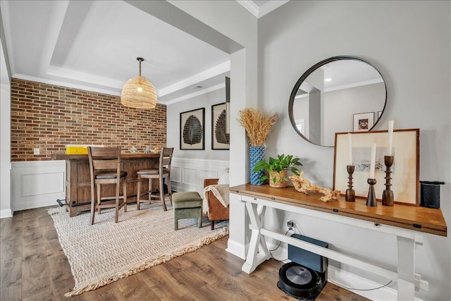 interior space with dark wood-style flooring, ornamental molding, a wainscoted wall, and a tray ceiling