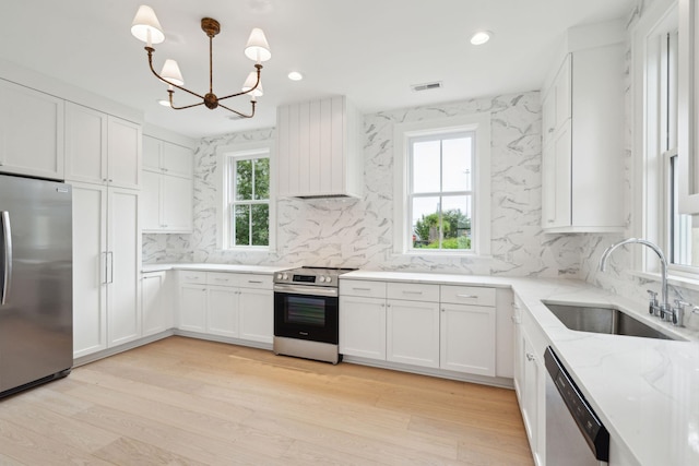 kitchen with stainless steel appliances, sink, white cabinetry, and a wealth of natural light