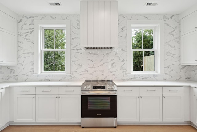 kitchen with light wood-type flooring, stainless steel electric stove, and white cabinets