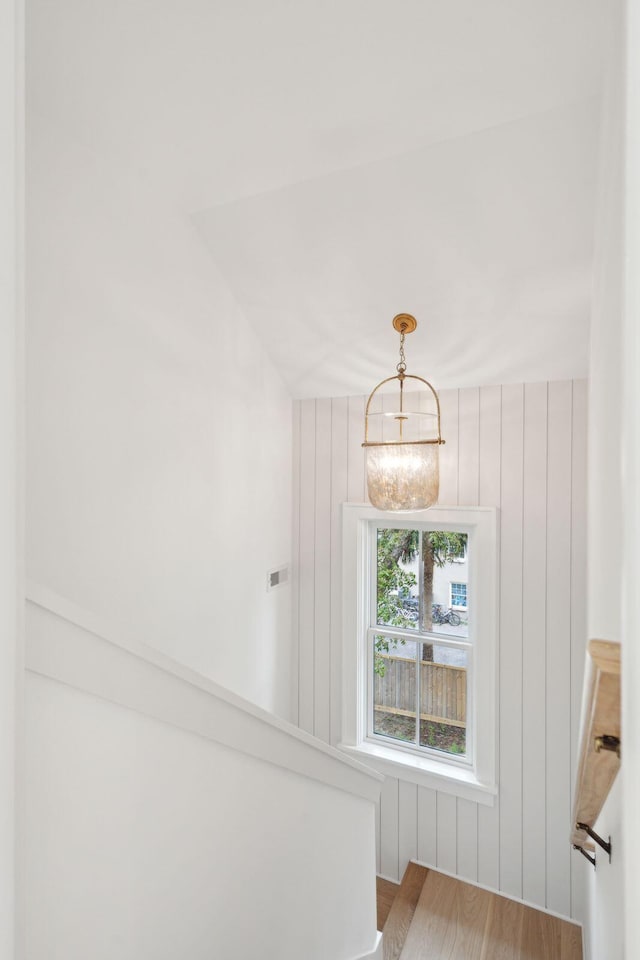 stairway featuring wood walls, an inviting chandelier, and hardwood / wood-style flooring