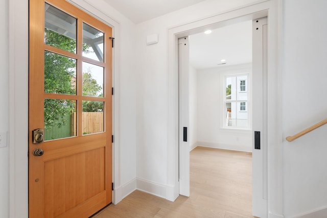 doorway with light wood-type flooring and a wealth of natural light