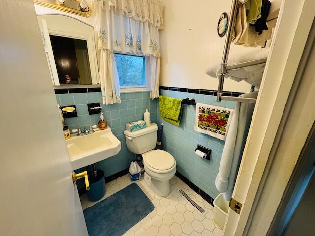 bathroom with sink, tile patterned flooring, tile walls, and toilet