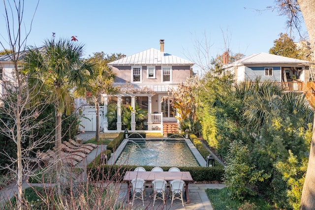 rear view of property with a patio, pool water feature, and an outdoor structure