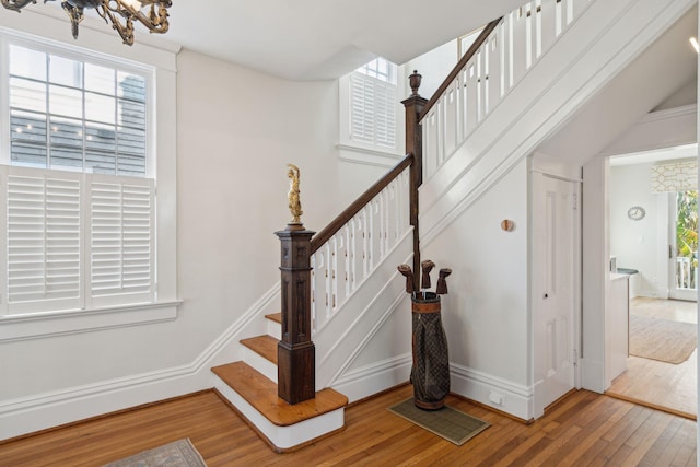 stairs with hardwood / wood-style floors and a notable chandelier