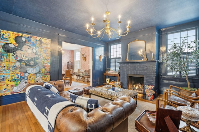 living room featuring a brick fireplace, a notable chandelier, and hardwood / wood-style flooring