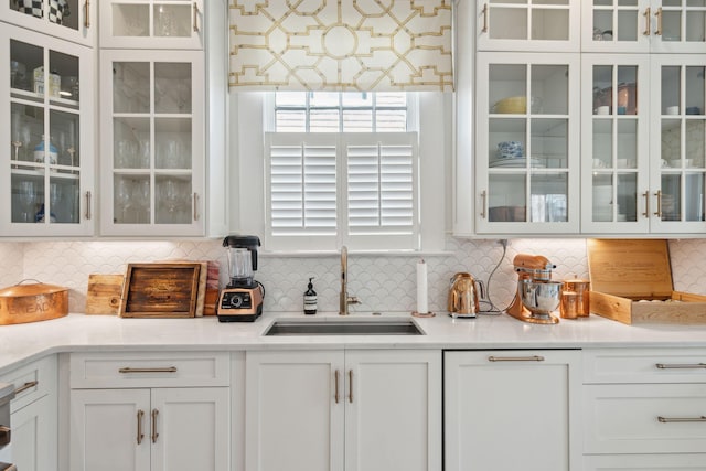 bar featuring tasteful backsplash, sink, and white cabinets