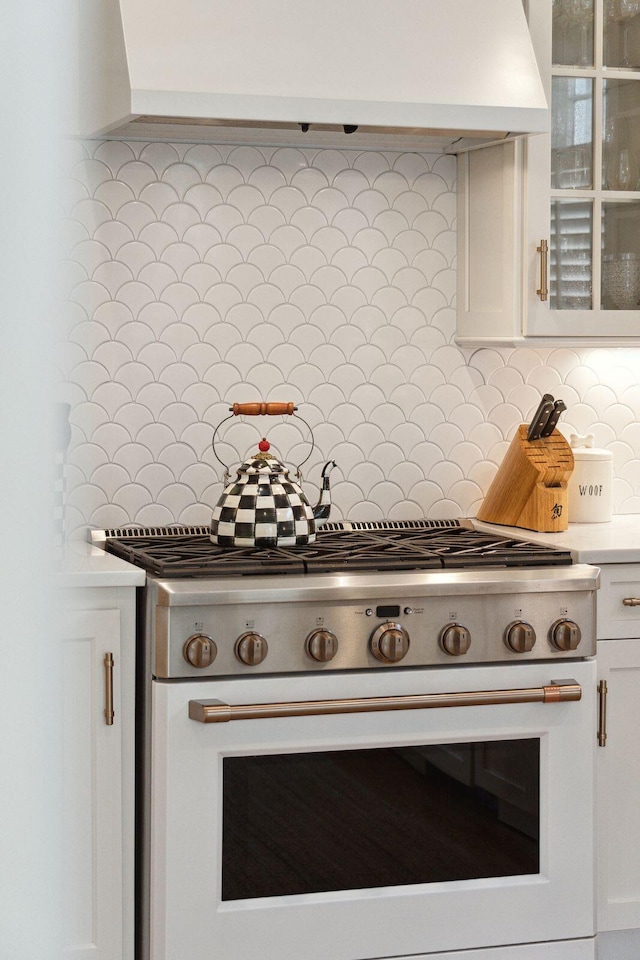 kitchen featuring white cabinetry, backsplash, custom exhaust hood, and white stove