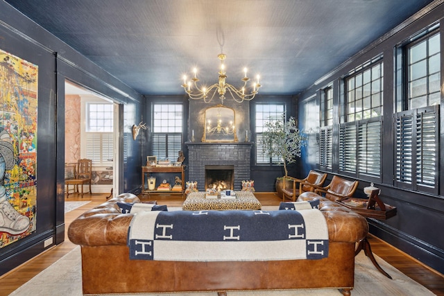 living room with hardwood / wood-style flooring, a brick fireplace, and an inviting chandelier