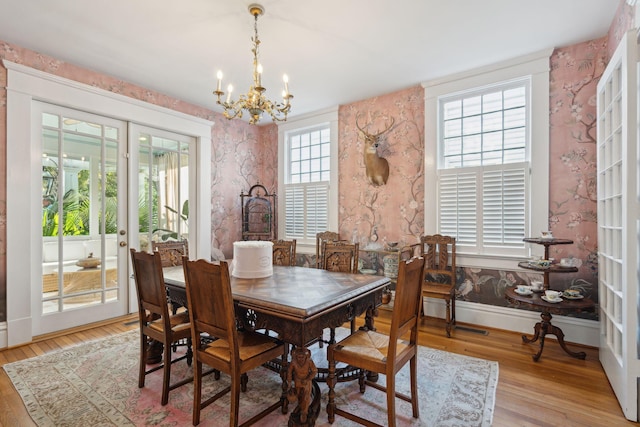 dining space with french doors, a chandelier, and light wood-type flooring