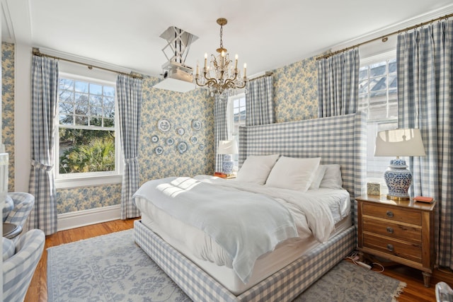 bedroom with multiple windows, wood-type flooring, and a chandelier