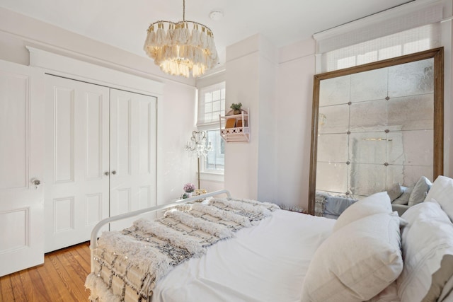 bedroom featuring an inviting chandelier, light hardwood / wood-style floors, and a closet