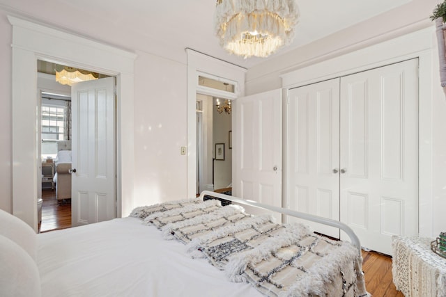 bedroom with hardwood / wood-style flooring, a chandelier, and a closet