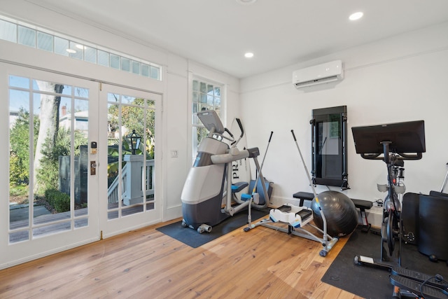 exercise area with a wall mounted air conditioner and hardwood / wood-style floors