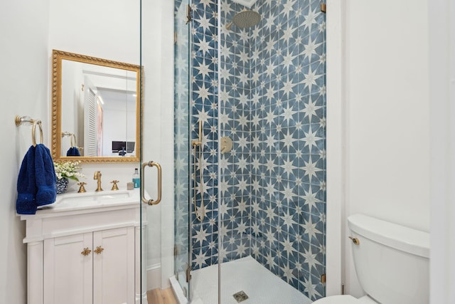 bathroom featuring a shower with door, vanity, and toilet