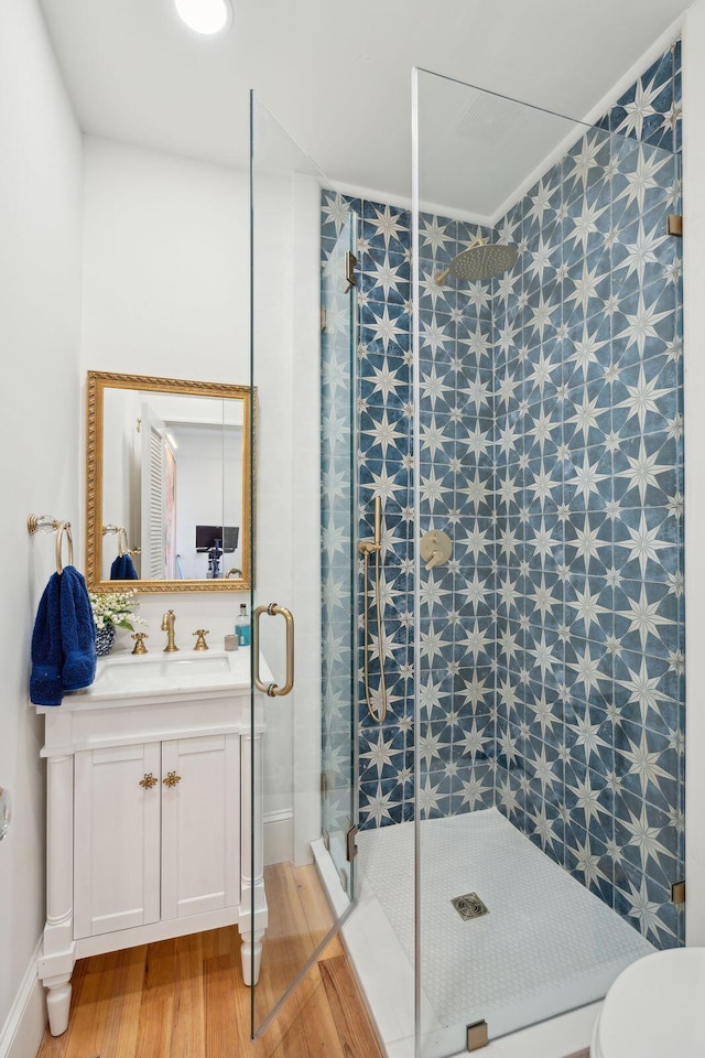 bathroom with walk in shower, vanity, and hardwood / wood-style floors