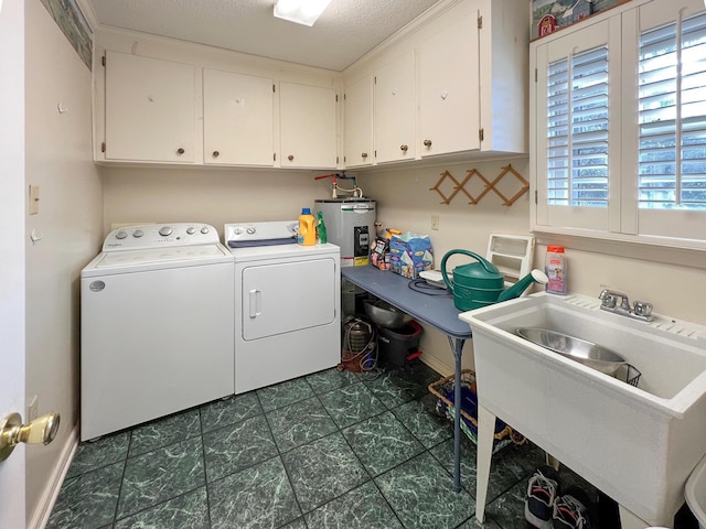 laundry area with cabinets, a textured ceiling, separate washer and dryer, and sink