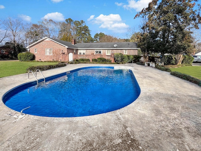 view of swimming pool featuring a patio area and a yard