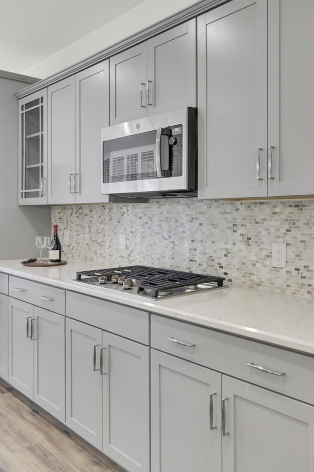 kitchen featuring tasteful backsplash, light wood-style floors, appliances with stainless steel finishes, and gray cabinets
