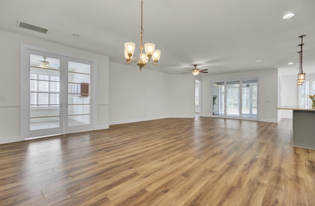 unfurnished living room featuring wood finished floors, ceiling fan with notable chandelier, baseboards, visible vents, and recessed lighting