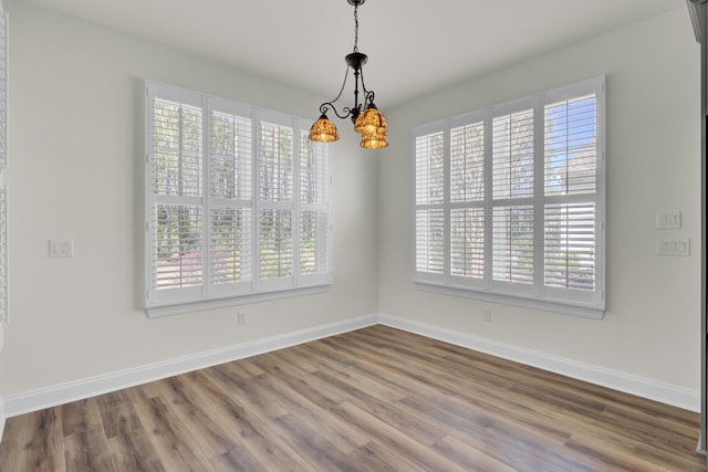unfurnished dining area with dark wood finished floors, a wealth of natural light, and baseboards