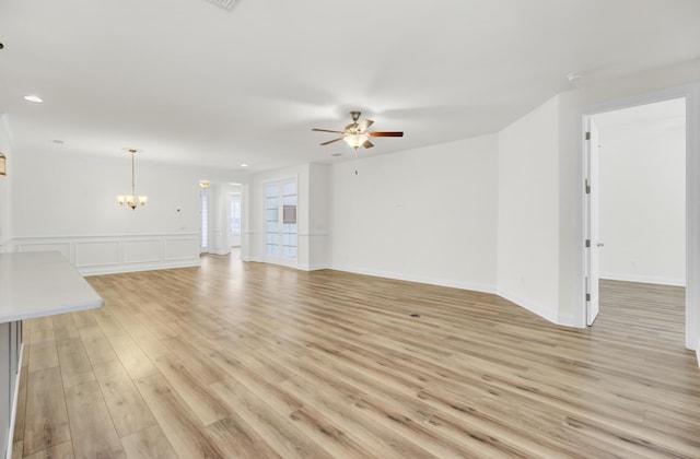 unfurnished living room featuring recessed lighting, light wood-type flooring, and ceiling fan with notable chandelier