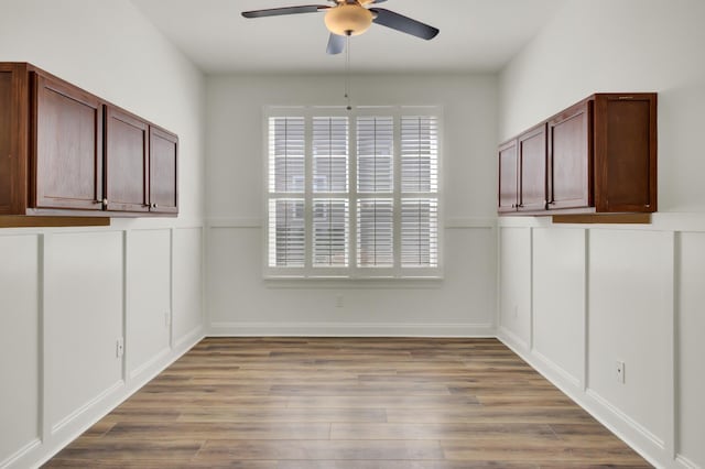 unfurnished dining area with a ceiling fan and wood finished floors