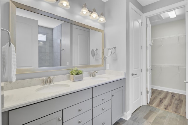 bathroom featuring double vanity, a spacious closet, and a sink