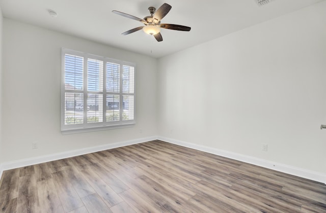 empty room featuring baseboards, a ceiling fan, wood finished floors, and plenty of natural light