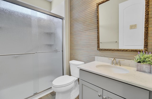bathroom featuring a shower stall, toilet, and vanity