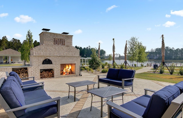 view of patio / terrace with a water view and an outdoor living space with a fireplace