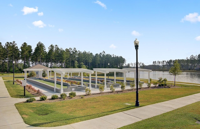 view of home's community with a pergola, a lawn, and a water view