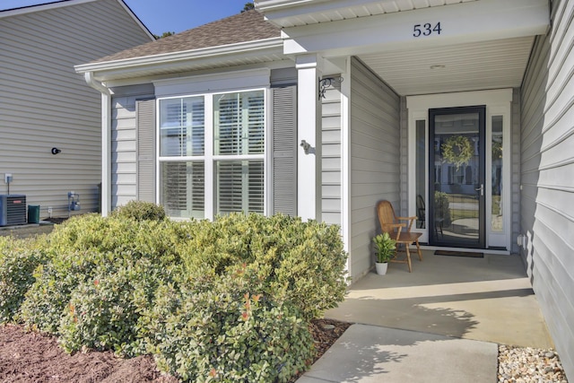 doorway to property with central AC and roof with shingles