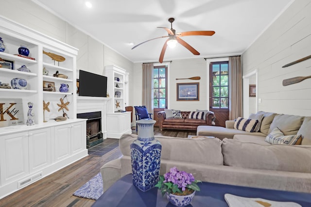 living room with dark hardwood / wood-style flooring, ceiling fan, and crown molding