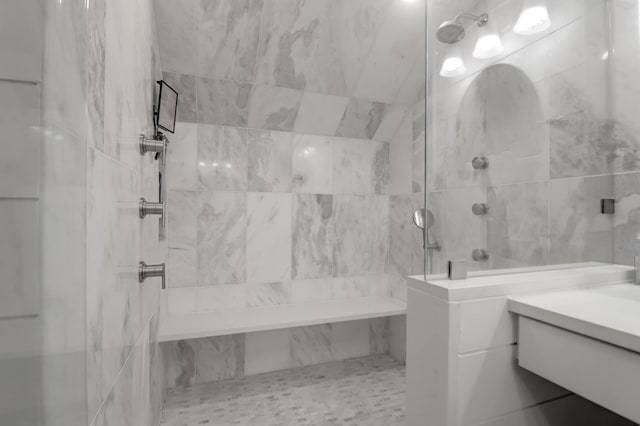 bathroom with vanity, tiled shower, and tile walls