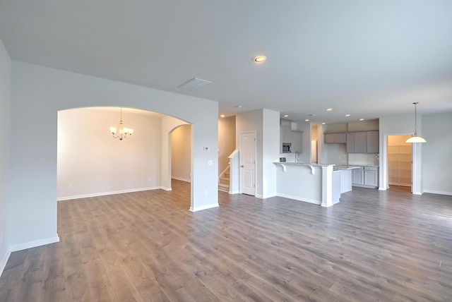 unfurnished living room with dark wood-type flooring and a notable chandelier