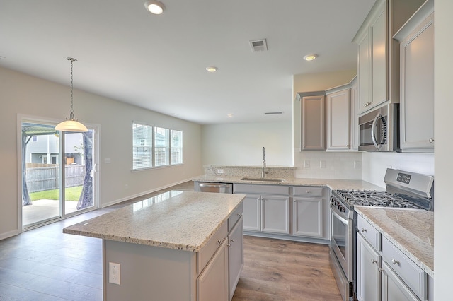 kitchen featuring sink, kitchen peninsula, decorative light fixtures, a kitchen island, and appliances with stainless steel finishes