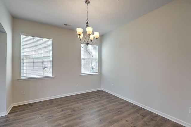 spare room featuring a notable chandelier and dark hardwood / wood-style floors